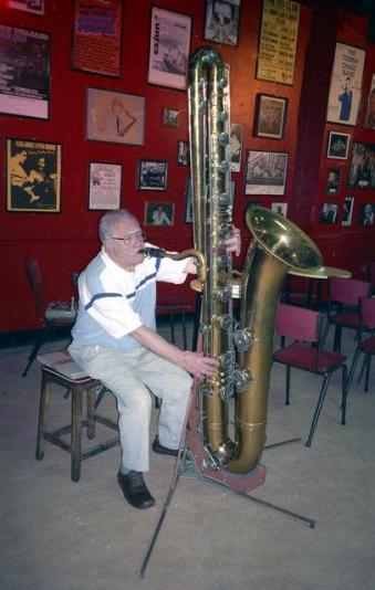 Bandleader Harry Gold playing a contrabass saxophone.