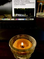 Candle in front of a headline about stabbings in Davis